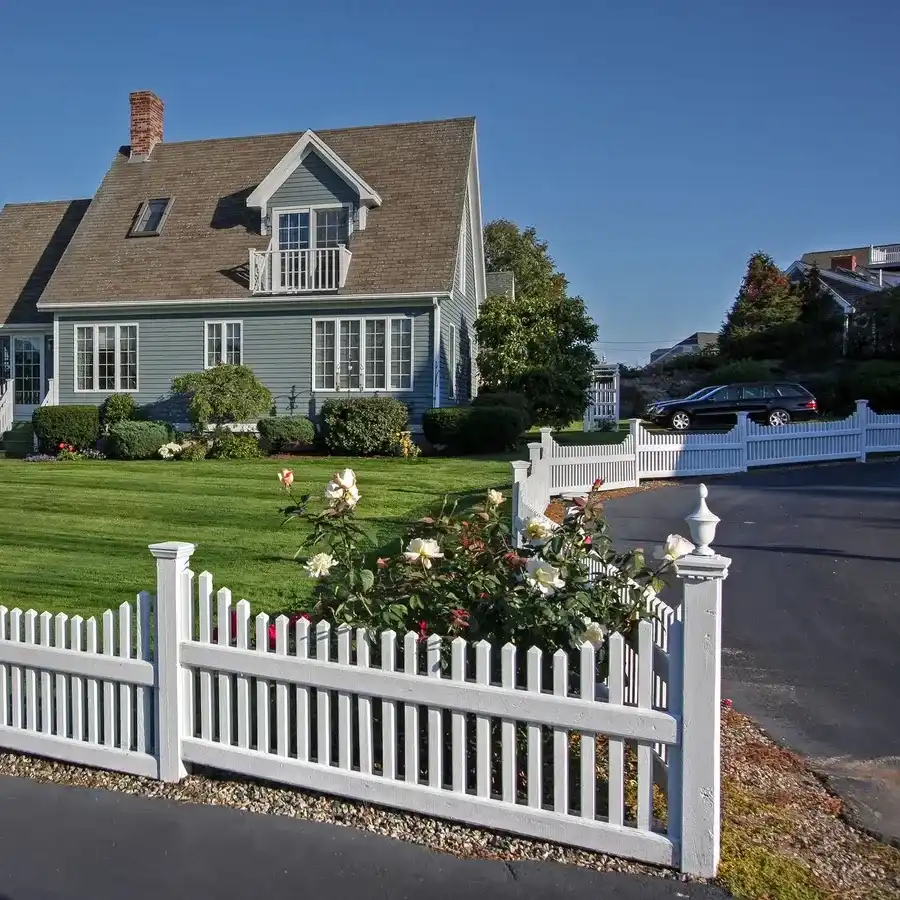 Home with a white picket fence and green lawn on a sunny day